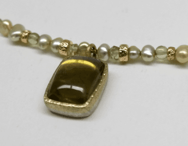 Detail of Yellow tourmaline set in 18 carat green gold, peridot beads, green pearls and 18 carat yellow gold beads